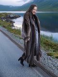 Woman walking in Canadian Raccoon Fur Coat along lakeside road, highlighting natural fur sheen and elegant cold-weather style.