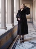 Woman in a black fur coat standing in an elegant interior setting with columns and marble floor.