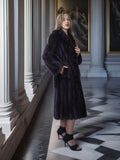 Woman wearing a long black fur coat in an elegant interior setting.