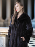 Woman wearing a black fur coat standing outdoors with blurred background