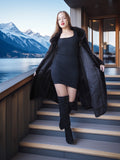 Woman in a black coat and dress standing on stairs with mountain and lake view