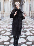 Model wearing La Galleria full-length mahogany mink fur coat with tie closure, styled in a grand architectural setting for winter fashion.
