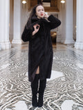 Model posing in La Galleria mahogany mink fur coat with tie-front, styled for elegant winter fashion in a grand architectural setting.