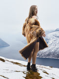 Model in vintage red fox coat on snowy cliff