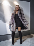 Woman wearing a fur coat and black knee-high boots in a modern interior setting.