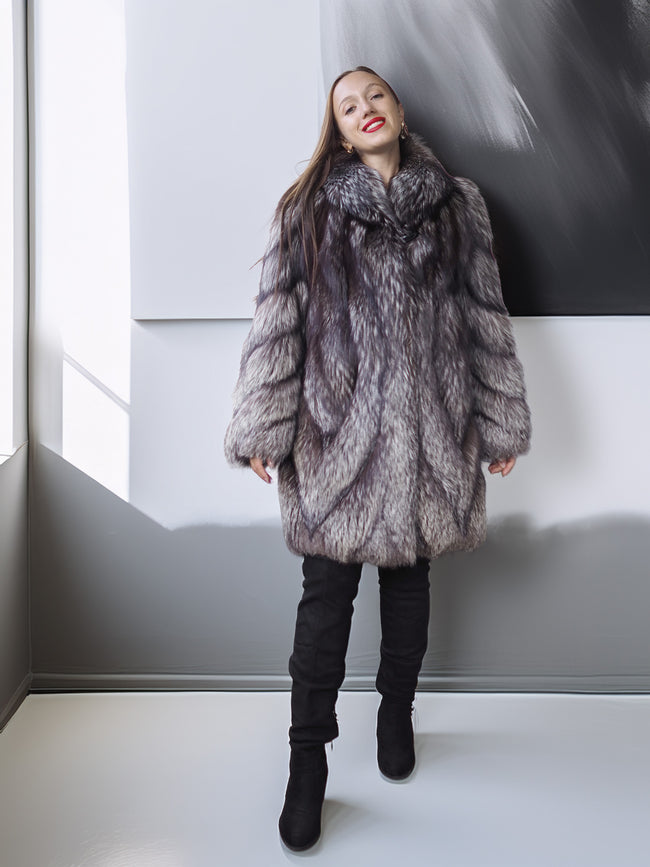 Person wearing a fur coat standing against a plain background