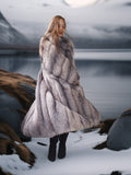 Woman in a fur coat standing on a snowy landscape with mountains in the background