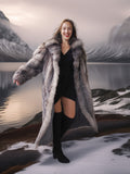 Woman in a fur coat standing in front of a mountainous landscape