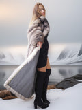 Woman in a fur coat standing in a snowy landscape with mountains in the background