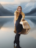 Woman wearing a fur vest standing in front of a scenic mountain landscape