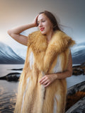 Woman wearing a fur vest standing in front of a scenic landscape
