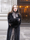Front view of black mink coat with silver fox collar, arms crossed to highlight warmth and plush fur texture.