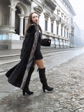 Black mink coat with silver fox collar draped off shoulder, revealing black mini dress for a bold winter look.