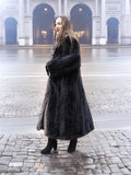 Side view of black mink coat with indigo fox collar, styled with black boots for a refined winter fashion statement.