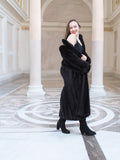 Model smiling in black mink fur coat worn off one shoulder, styled with black boots. Full-length fur fashion for winter, size M.