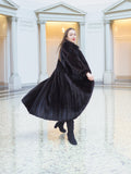 Flowing black mink fur coat in motion, highlighting its regal volume and luxurious sheen. Full-length fur fashion for winter, size M.