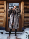 Woman in a fur coat standing in front of a wooden door with snow on the ground