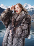 Woman in a fur coat standing in front of a mountainous landscape with a lake.