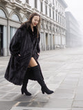 Black mink fur coat styled for winter street fashion, combining elegance with comfort in a full-length silhouette.