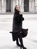 Black mink fur coat with a flowing silhouette, styled with boots for a fashionable and cozy winter outerwear look.