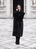 Model poses in a full-length black mink fur coat with arms crossed, showcasing its plush texture and elegant fit.