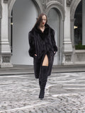 Full-length black mink fur coat styled with thigh-high boots, perfect for elegant winter fashion in urban settings.