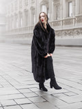 Model in a black mink fur coat walking on a foggy street, highlighting the coat’s warmth and luxurious appeal.