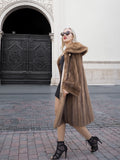 Luxurious pastel brown mink fur coat with vintage design, worn by elegant woman in front of ornate wooden doors.
