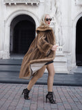 Luxurious pastel brown mink fur coat on stylish model, showcasing high-end fashion accessories in front of ornate architectural backdrop.