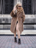Elegant woman in pastel Canadian brown mink fur coat, stylishly posed in front of ornate building.