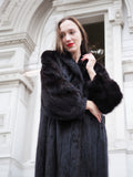 Close-up of black mink fur coat showing plush texture and classic collar, highlighting premium craftsmanship in fur apparel.