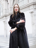 Close-up of woman in black mink fur coat with detailed sleeve texture and classic collar, perfect for luxury fur fashion.