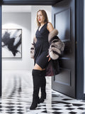 Woman in a stylish outfit with a fur coat standing in a modern interior setting.