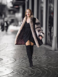 Woman in a fur coat and black dress walking on a city street.