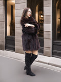 Mahogany mink coat styled with arms crossed, perfect for elegant winter outerwear in a neutral cityscape.