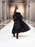Woman spinning in Midnight Sonata black mink coat, revealing the coat’s luxurious fullness and graceful movement indoors.