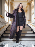 Woman in a long dark fur coat standing on a staircase in an elegant interior setting