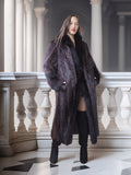 Woman wearing a long dark fur coat in an elegant interior setting