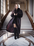 Woman in a long black fur coat standing in an elegant staircase.