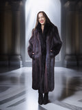 Woman wearing a long dark fur coat in an elegant interior setting