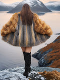 Back view of The Wild Muse fox fur coat in red and gray hues, flared dramatically in a cinematic mountain setting.