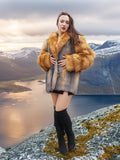 Red and gray fox fur coat by The Wild Muse, styled with thigh-high boots in a Nordic mountain setting for a bold winter fashion statement.