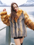 The Wild Muse luxury fur coat in natural red and gray fox, worn on a lakeside deck, showcasing its plush texture and elegant silhouette.