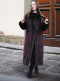 Model adjusts collar of red and black mink fur coat, showcasing its unique two-tone design and vintage appeal.