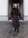 Smiling model wears red and black mink fur coat with hands in pockets, ideal for elegant winter outerwear styling.