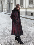Model walks along textured pavement in red and black mink fur coat, highlighting its elegant and sustainable design.