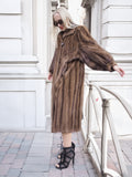 Vintage Canadian brown mink fur coat with silk lining, showcased in a dramatic pose on a city street.