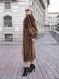 Elegant woman in long brown mink fur coat and high heels posing on city street.