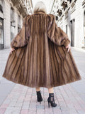 Elegant pastel brown mink fur coat with silk lining, showcased on a cobblestone city street.