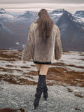 Model walking away in Raccoon Glamour Jacket - Mountain Mirage S/M, showcasing fur texture and winter fashion movement.